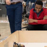 a person smiling a a small robot that is a part of a senior project